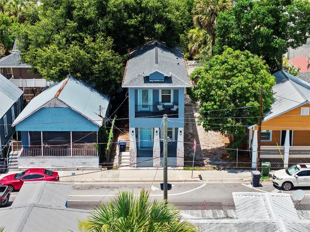 An aerial view shows a narrow, two-story blue house situated between two other residential buildings — 2106 E 17TH AVENUE, TAMPA, FL
