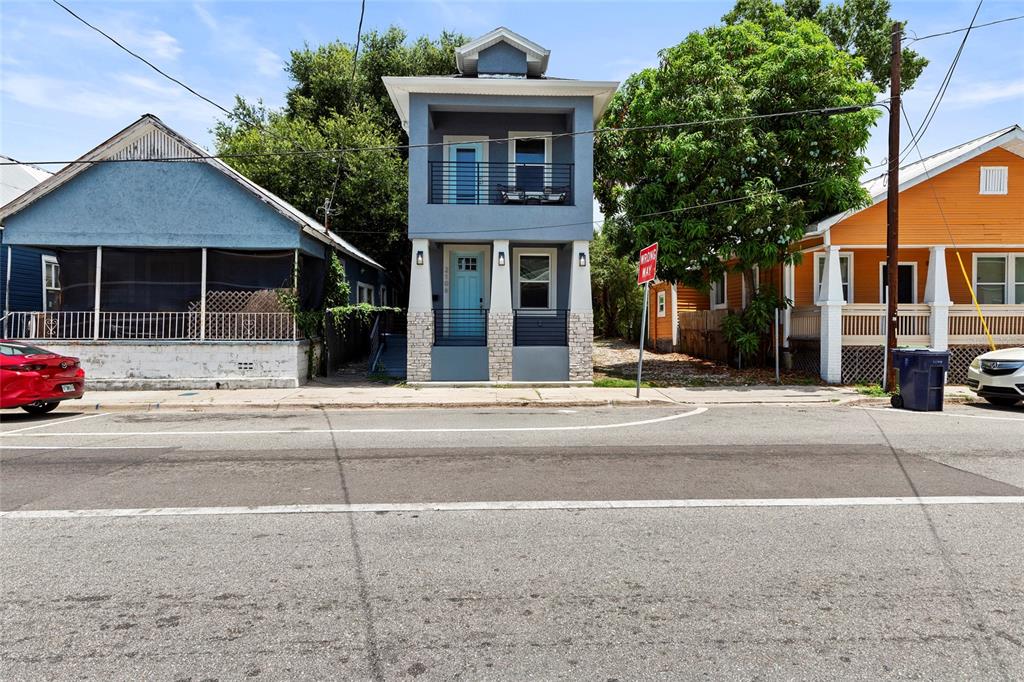 A narrow, two-story blue house with a front porch sits between two other residential buildings — 2106 E 17TH AVENUE, TAMPA, FL