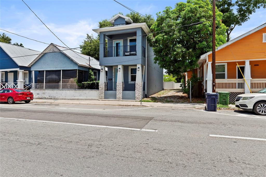 A narrow, two-story blue house stands between two single-story homes on a paved street — 2106 E 17TH AVENUE, TAMPA, FL