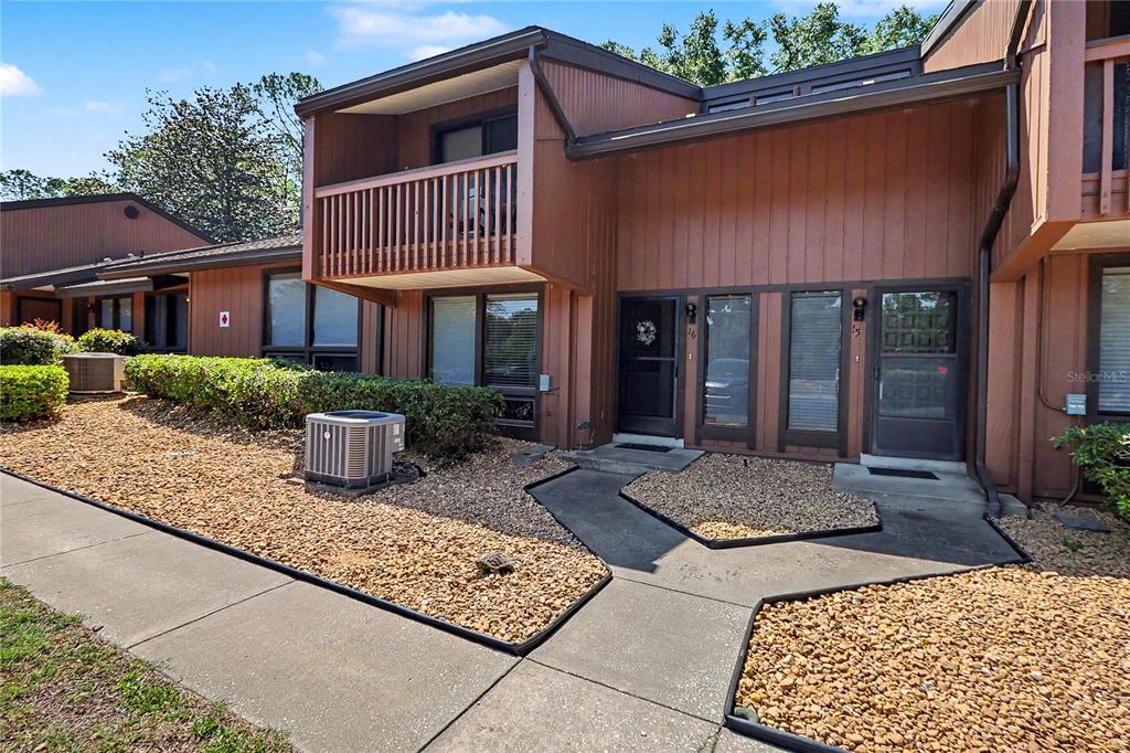 A two-story brown townhouse exterior features a balcony, gravel landscaping, and concrete walkways — 19660 SW 83RD PLACE ROAD UNIT C16, DUNNELLON, FL