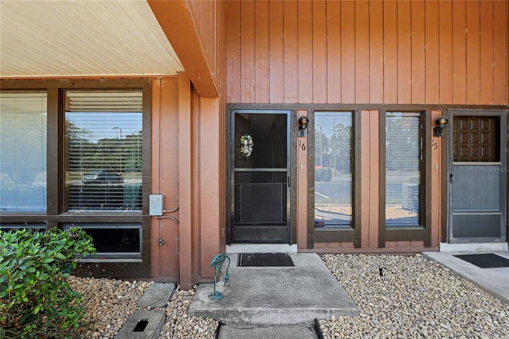 The exterior of a residential building features a brown wood-paneled facade and two entry doors — 19660 SW 83RD PLACE ROAD UNIT C16, DUNNELLON, FL