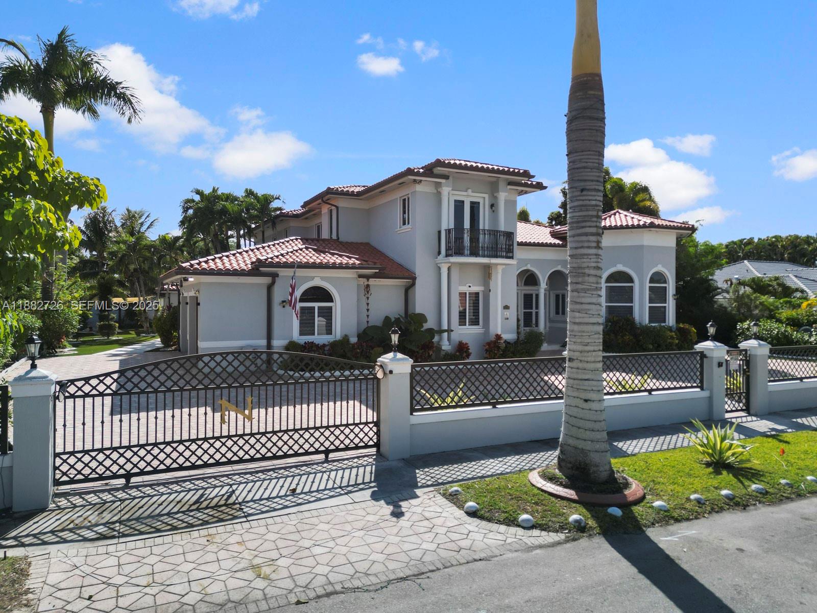 A two-story house with a tiled roof, gated driveway, and a tall palm tree — 12770 SW 188th St, Miami FL 33177, MIAMI, FL