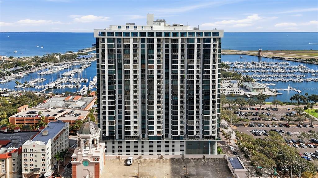 An aerial view shows a tall residential high-rise building situated near a marina and harbor — 1 BEACH DRIVE SE UNIT 1610, ST PETERSBURG, FL