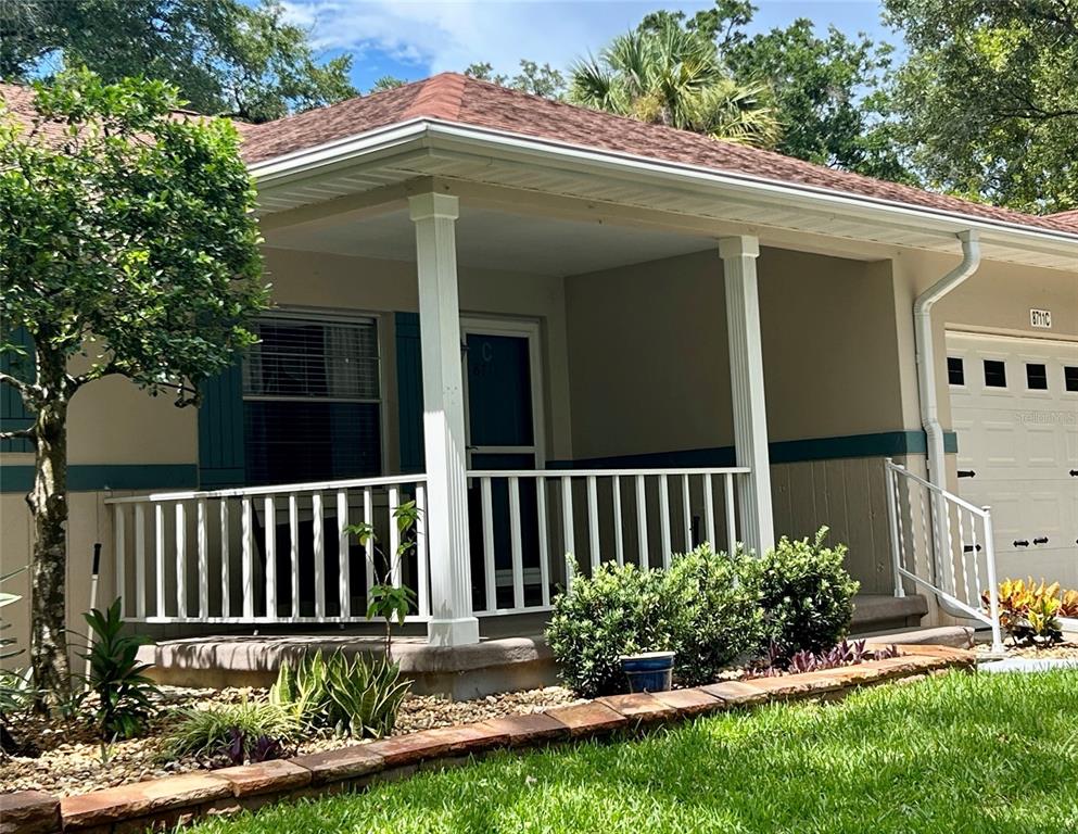 A house exterior features a covered front porch with white railings and a garage — 8711 SW 96TH LANE UNIT C, OCALA, FL