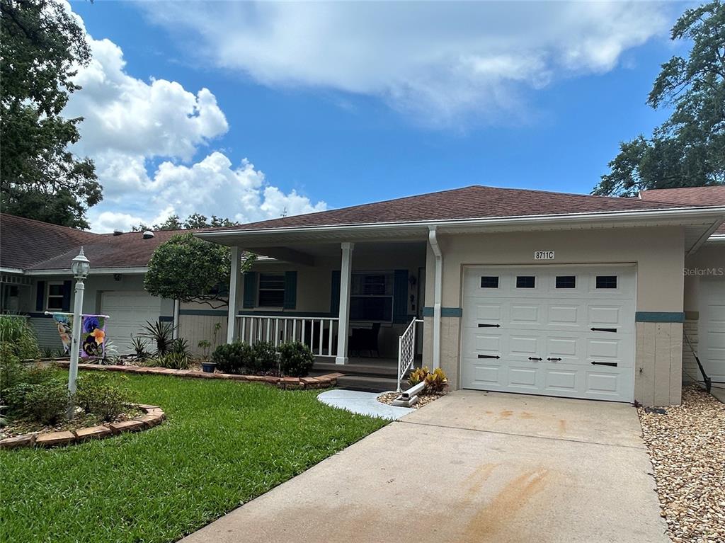 A single-story house features a white garage door, a covered front porch, and a lawn — 8711 SW 96TH LANE UNIT C, OCALA, FL