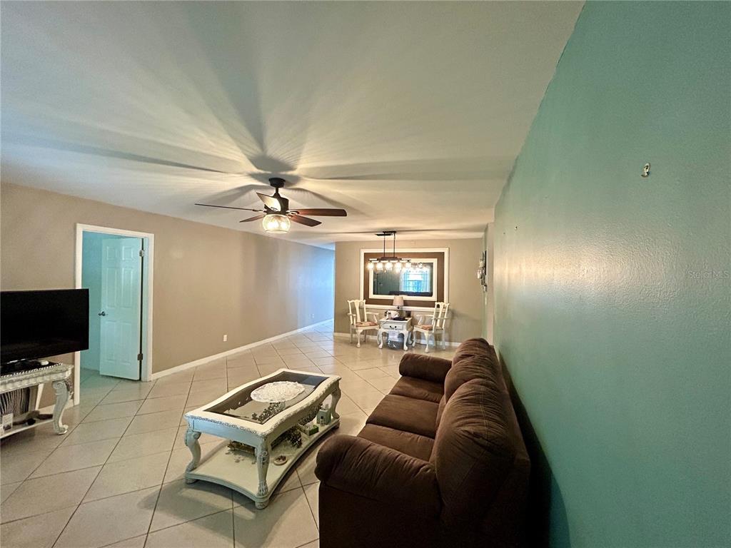 A living room with tile floors, a brown sofa, a coffee table, and a ceiling fan — 8711 SW 96TH LANE UNIT C, OCALA, FL