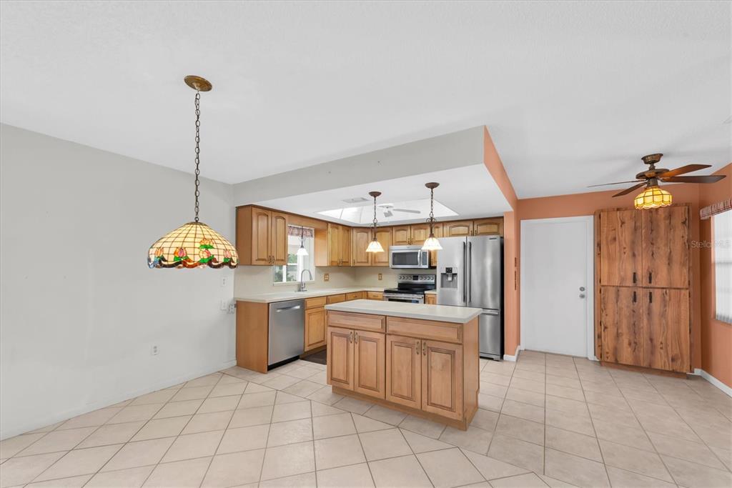A kitchen with wood cabinets, a center island, stainless steel appliances, and tile flooring — 12939 115TH STREET, LARGO, FL