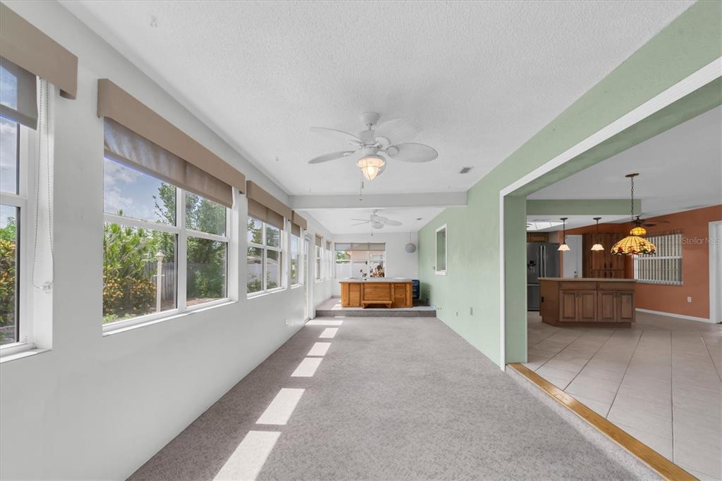 A sunroom with gray carpeting, a hot tub, and a view into the adjacent kitchen — 12939 115TH STREET, LARGO, FL