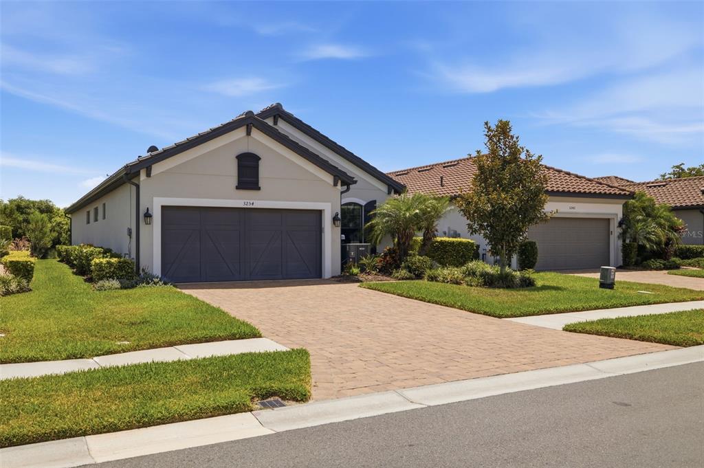 A single-story house with a two-car garage and a paved driveway under a blue sky — 3254 FRANCOA DRIVE, ODESSA, FL