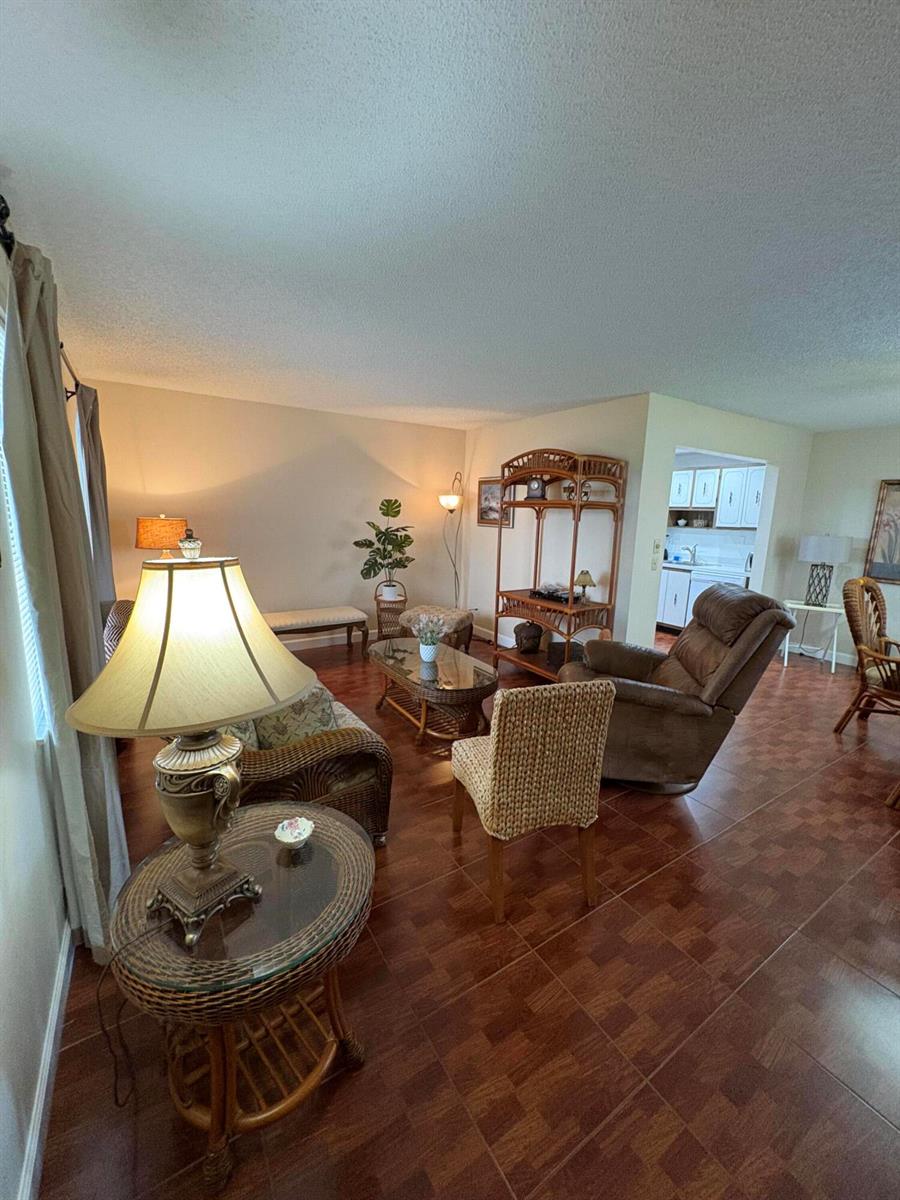 A living room features wicker furniture, a brown recliner, and tile flooring — 23 Flanders A, Delray Beach FL 33484, DELRAY BEACH, FL