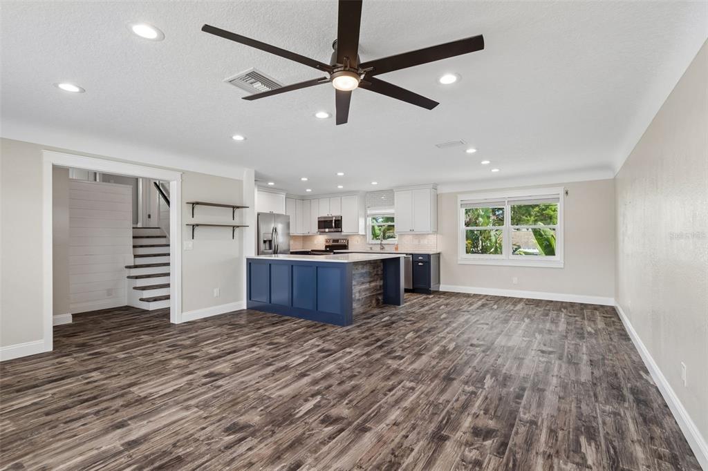 An open-concept kitchen features a blue island, white cabinetry, and wood-look flooring — 13548 BELLEWOOD AVENUE, SEMINOLE, FL