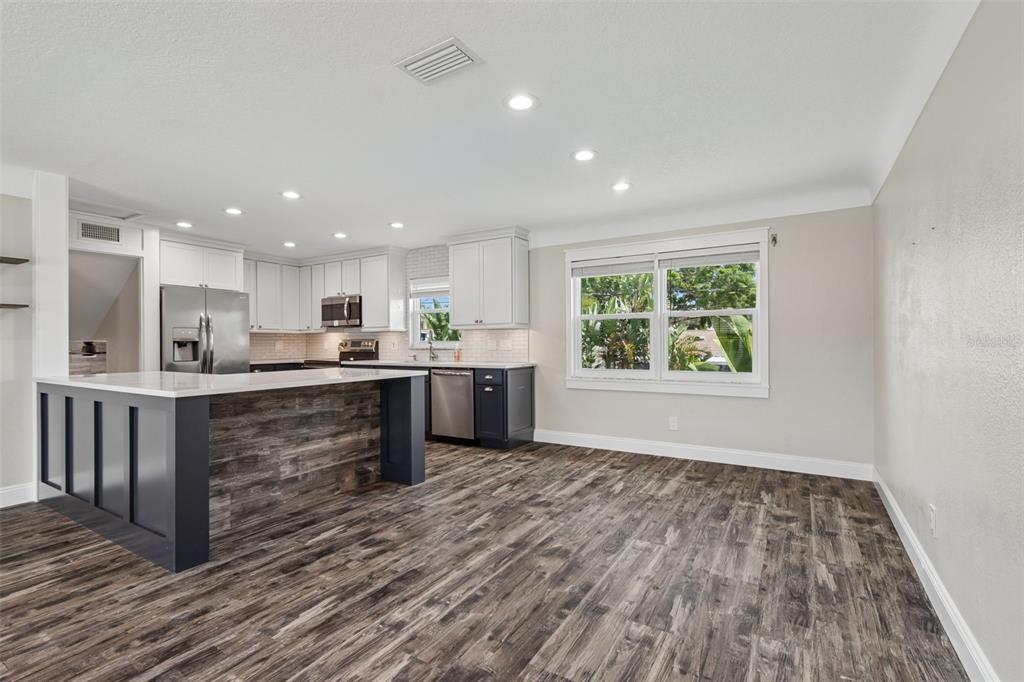 A kitchen features a wood-paneled island, white upper cabinets, dark lower cabinets, and wood-look flooring — 13548 BELLEWOOD AVENUE, SEMINOLE, FL