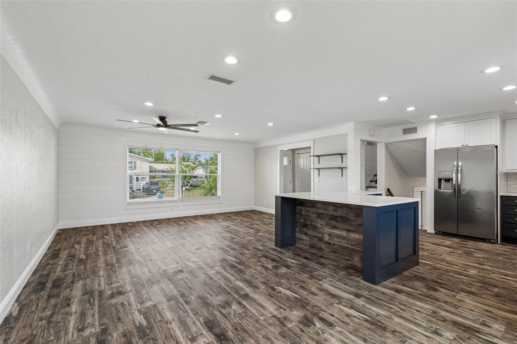 A kitchen and living area featuring wood-look flooring, a blue island, and white shiplap walls — 13548 BELLEWOOD AVENUE, SEMINOLE, FL
