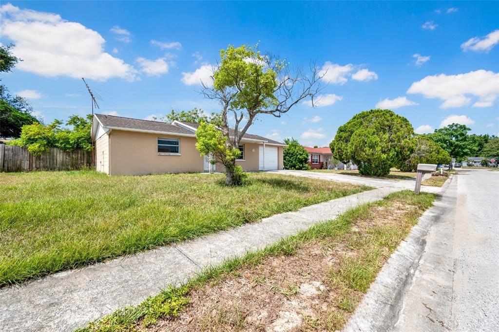 A tan, single-story house with a garage and a tree in the front yard — 6318 BALDWYN AVENUE, NEW PORT RICHEY, FL
