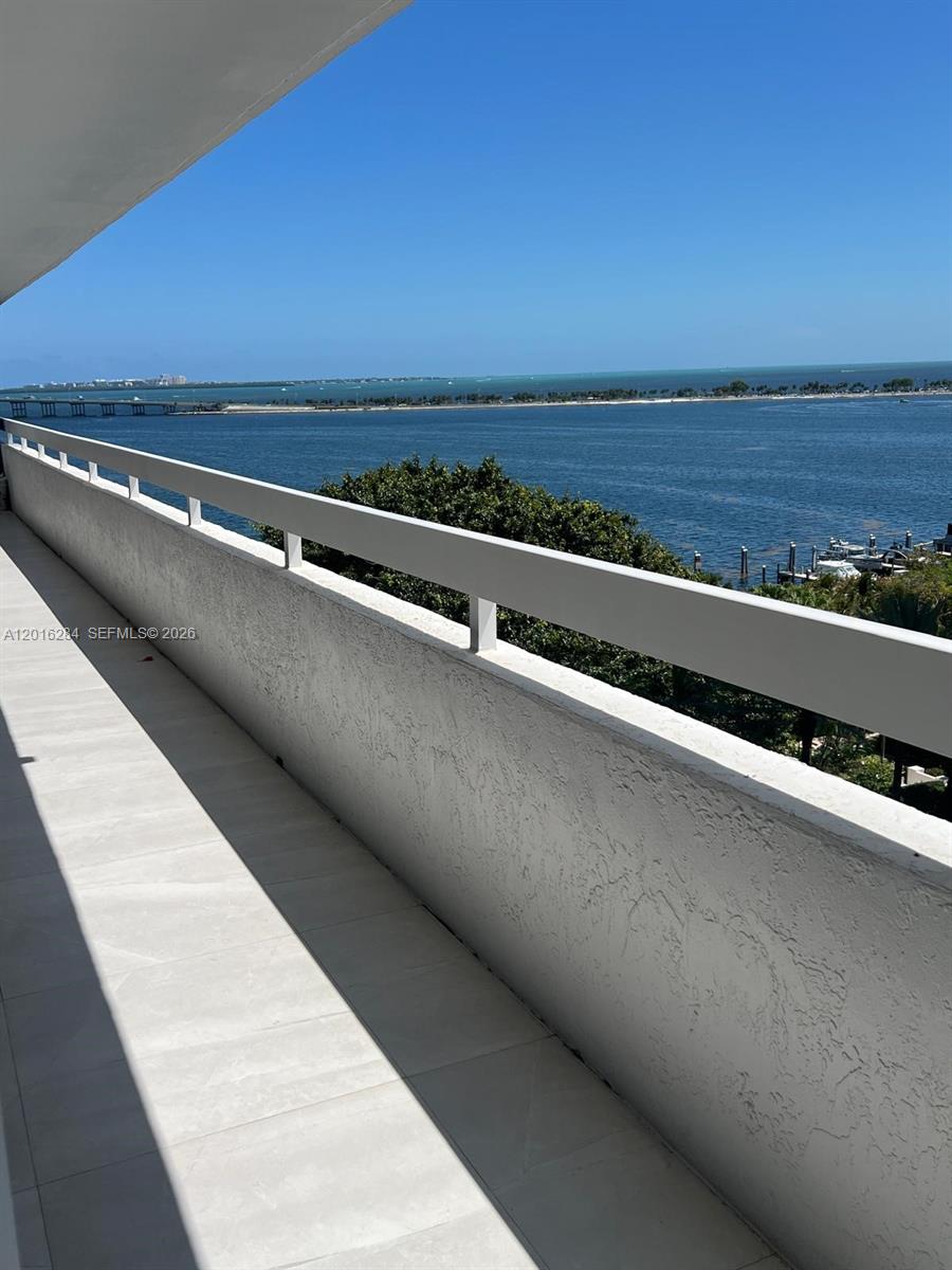 A balcony with a white railing overlooks a bay with a bridge and boats — 1627 Brickell Ave # 1204, Miami FL 33129, MIAMI, FL