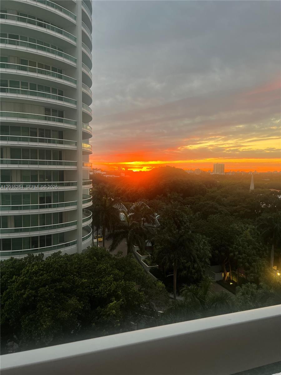 A high-rise building overlooks a lush green landscape during a vibrant sunset — 1627 Brickell Ave # 1204, Miami FL 33129, MIAMI, FL