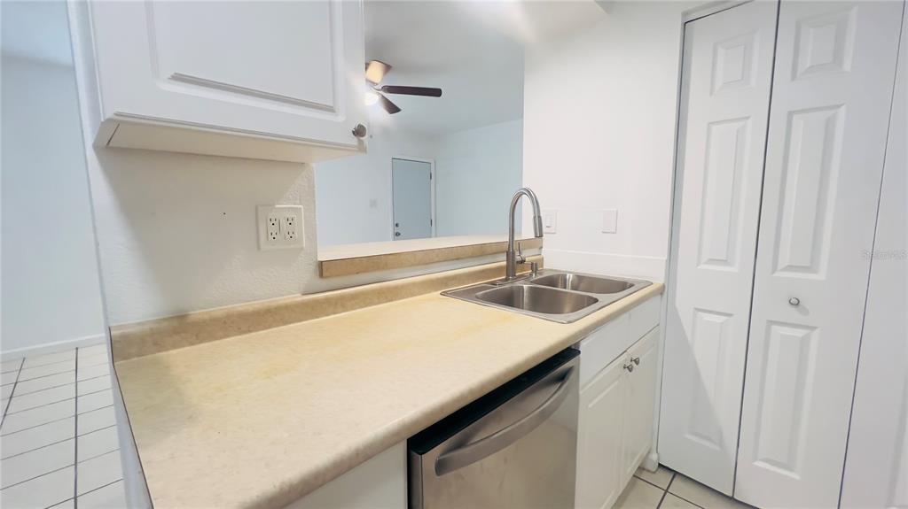 A kitchen features white cabinets, a stainless steel sink, a dishwasher, and a pass-through window — 5301 40TH STREET N, ST PETERSBURG, FL