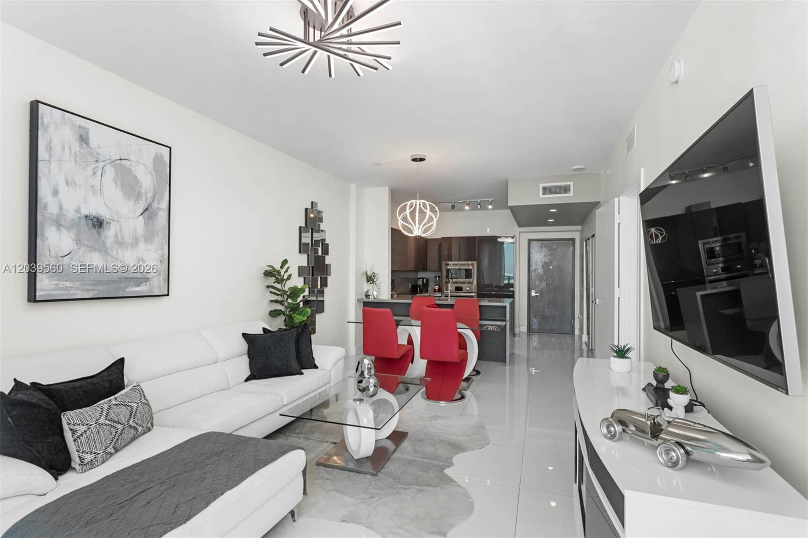A modern living and dining area features white tile floors, a white sofa, and red chairs — 1080 Brickell Ave # 4103, Miami FL 33131, MIAMI, FL