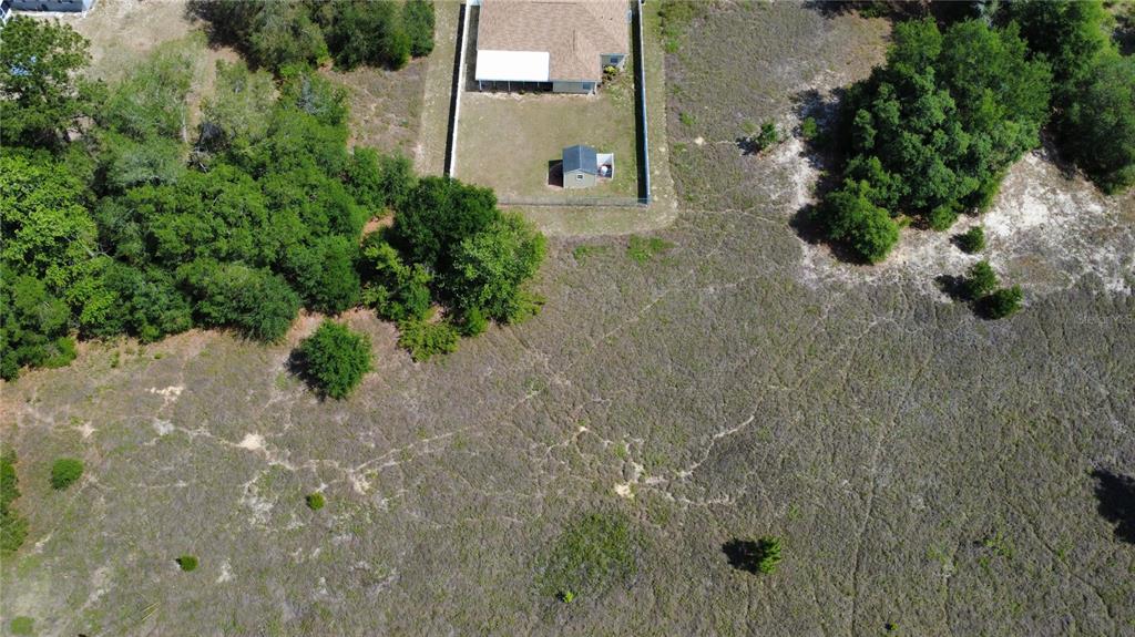 An aerial view shows a house with a fenced backyard and shed beside a wooded area — SW BEACH BOULEVARD, DUNNELLON, FL
