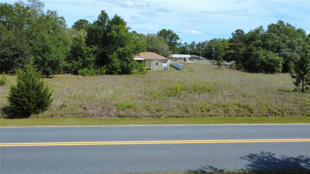 A vacant, grassy lot sits beside a paved road with a small shed in back — SW BEACH BOULEVARD, DUNNELLON, FL