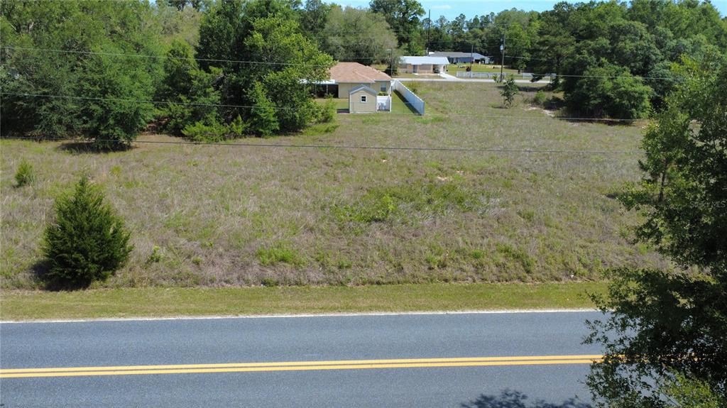 An aerial view shows a vacant, grassy lot situated next to a house and shed — SW BEACH BOULEVARD, DUNNELLON, FL