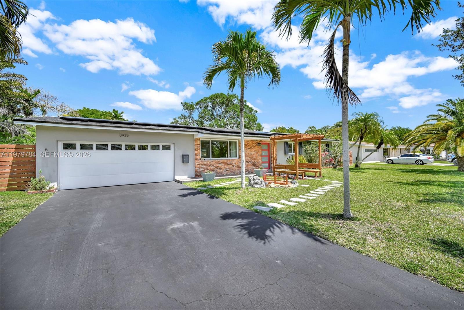 A single-story house with a brick facade, white garage, and a wooden pergola in front — 8935 SW 186th Ter, Cutler Bay FL 33157, CUTLER BAY, FL