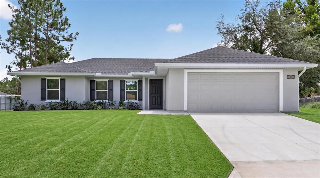 A single-story gray house with a two-car garage and a green lawn — 13 PECAN DRIVE LOOP, OCALA, FL