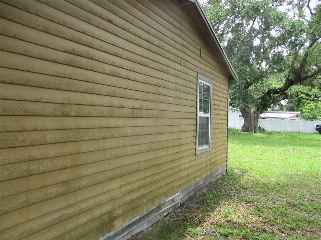 An exterior view of a house side wall with yellow horizontal siding and a window — 302 E 130TH AVENUE, TAMPA, FL
