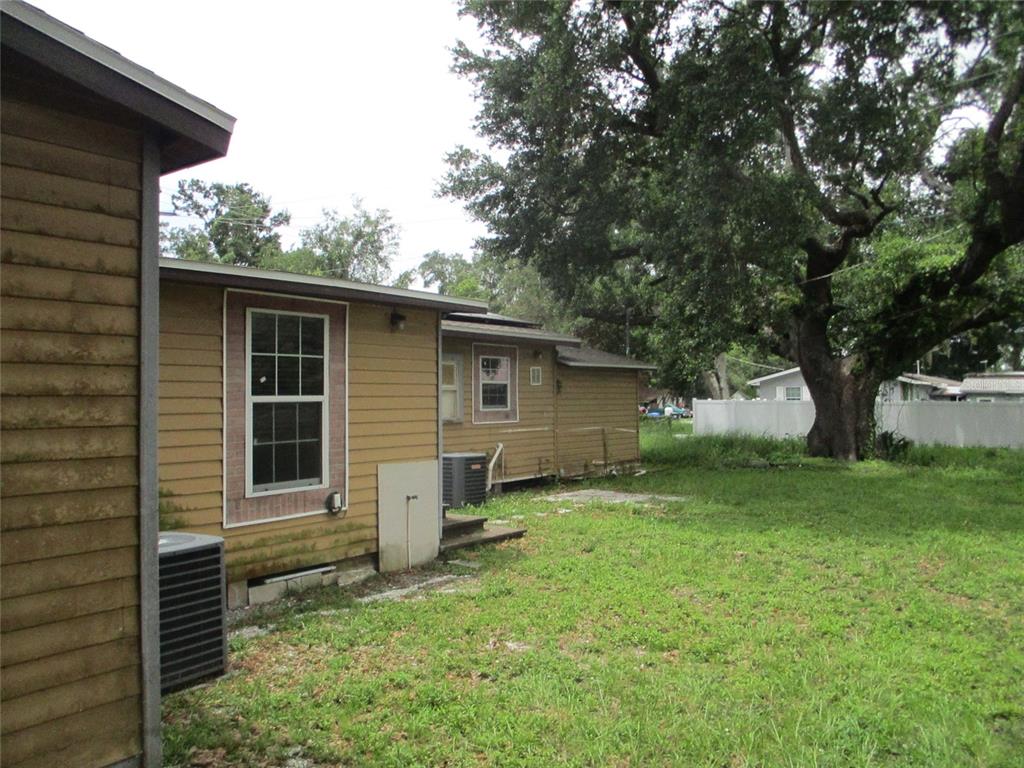 The exterior of a tan, single-story house with a grassy yard and a large tree — 302 E 130TH AVENUE, TAMPA, FL
