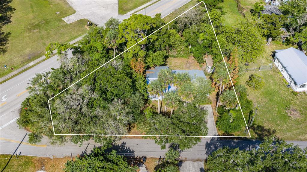 An aerial view shows a house surrounded by trees on a triangular-shaped lot — 240 NEWCOMB STREET, NEW SMYRNA BEACH, FL