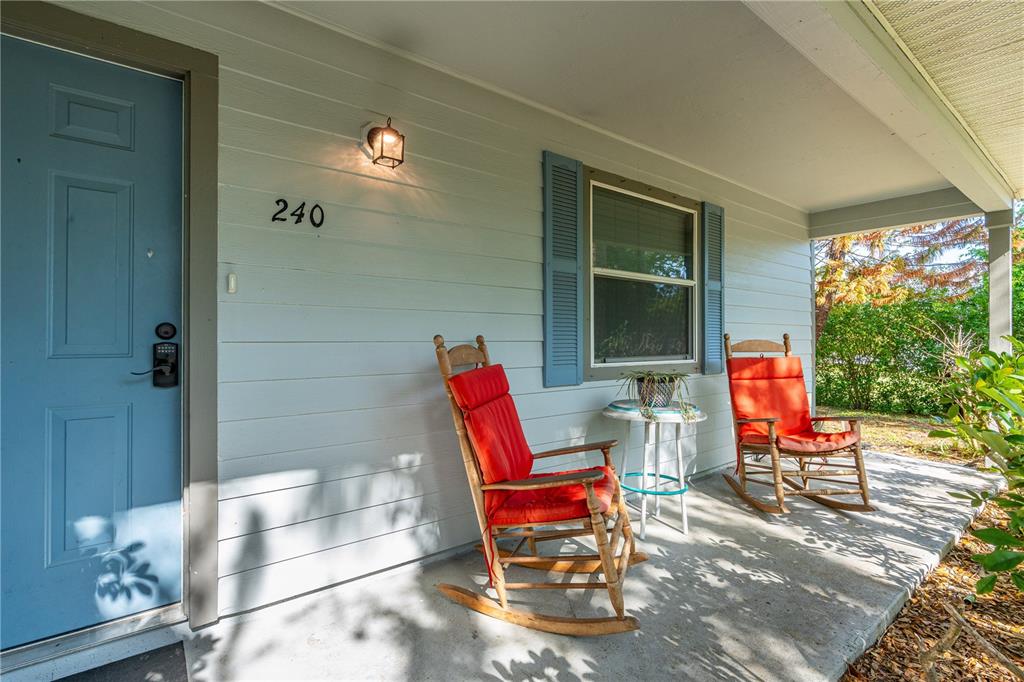 A front porch features a blue door, two wooden rocking chairs, and a small table — 240 NEWCOMB STREET, NEW SMYRNA BEACH, FL