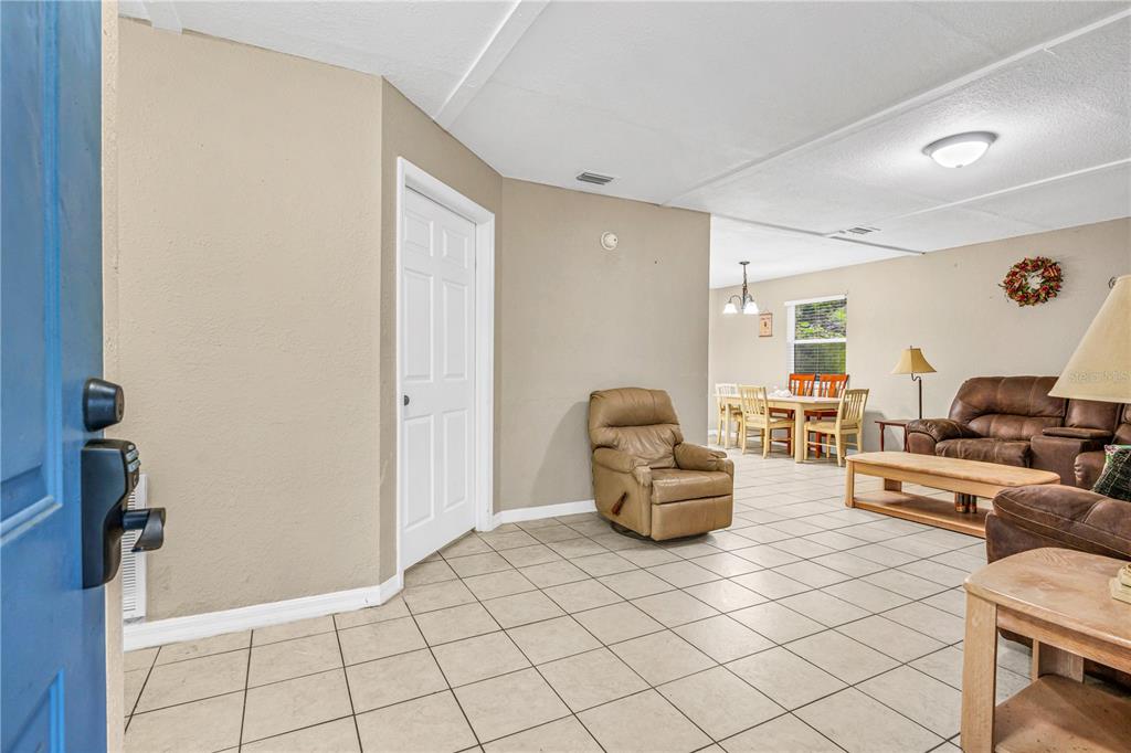 An open-concept living and dining area features tile flooring, beige walls, and brown furniture — 240 NEWCOMB STREET, NEW SMYRNA BEACH, FL