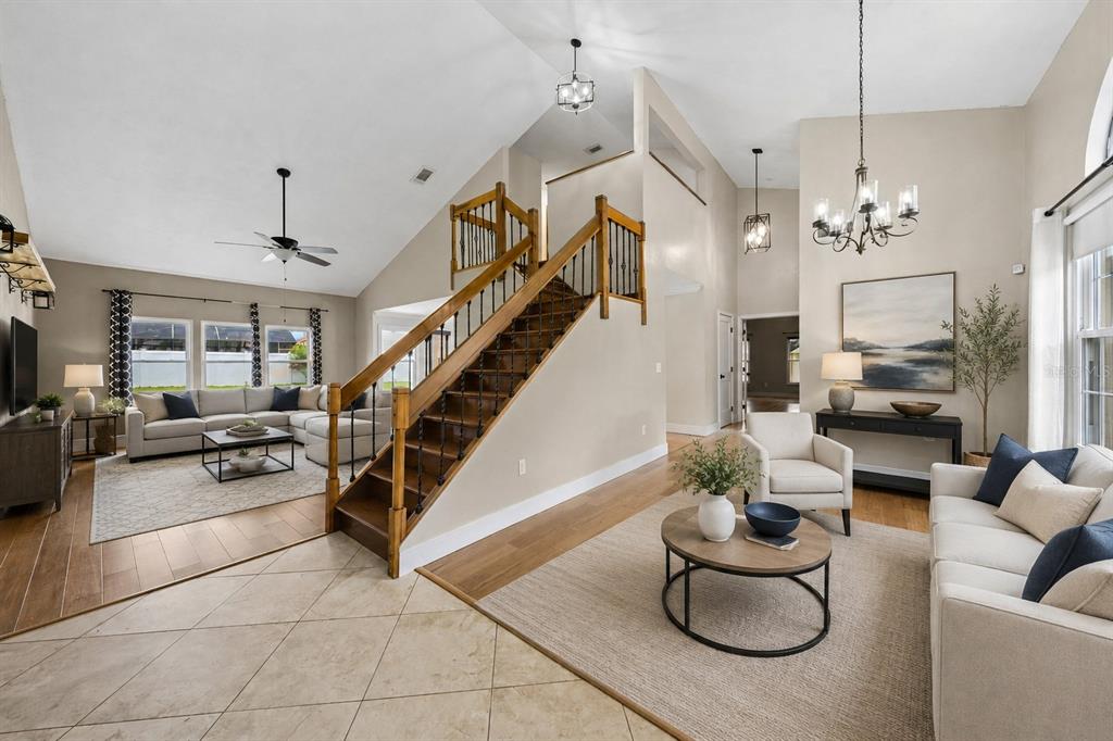 A living room with a staircase, vaulted ceilings, tile and wood flooring, and neutral furniture — 1714 CYPRESS RIDGE DRIVE, ORLANDO, FL