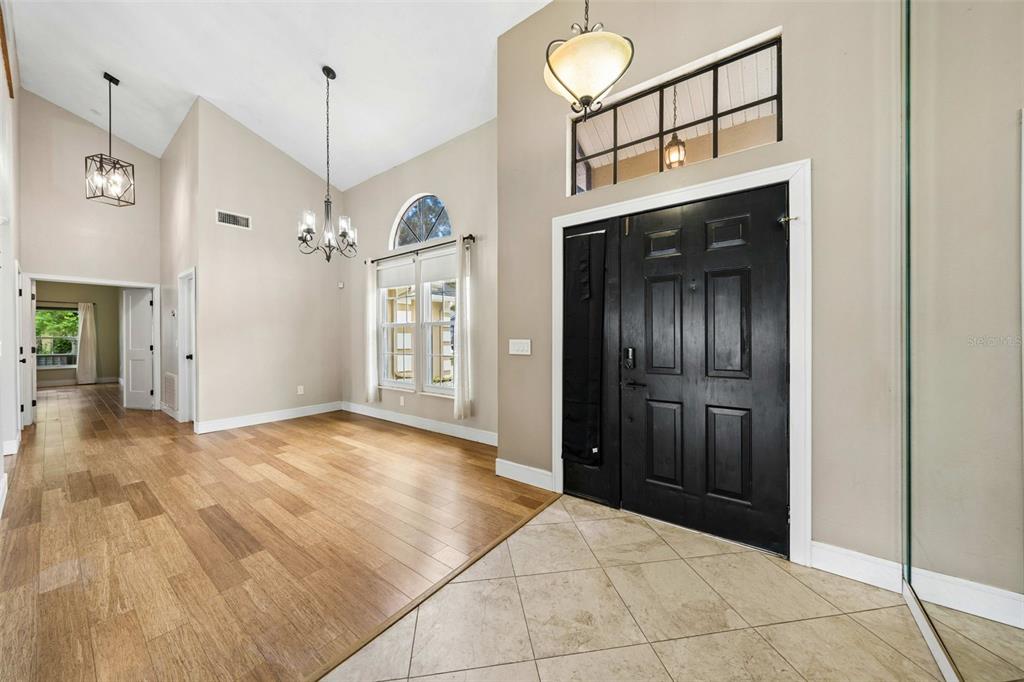 An entryway with tile flooring transitions to wood floors in a room with vaulted ceilings — 1714 CYPRESS RIDGE DRIVE, ORLANDO, FL