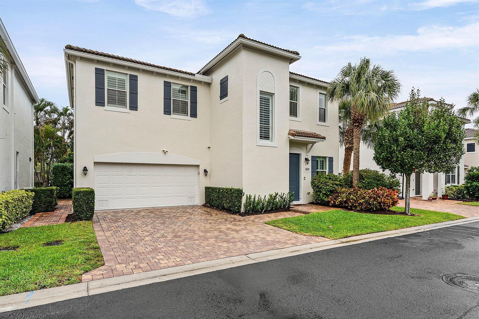 A two-story stucco house features a two-car garage, a paved driveway, and a palm tree — 409 Francesca Ridge Road, Boynton Beach FL 33435, BOYNTON BEACH, FL
