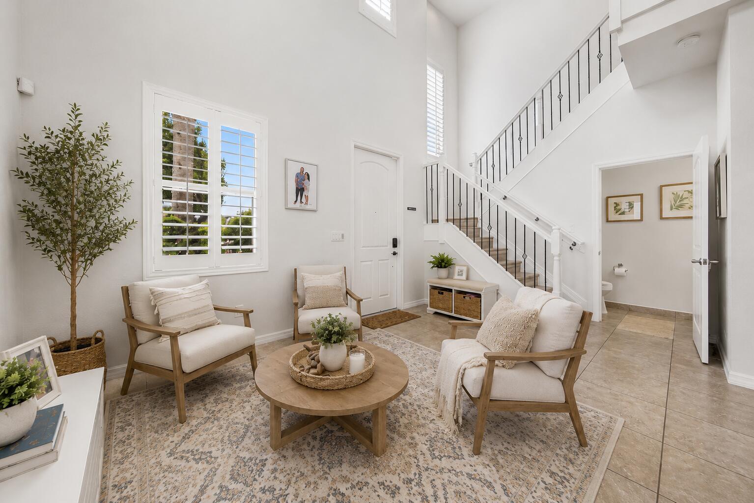 A bright entryway features a staircase, three armchairs, a round coffee table, and tile flooring — 409 Francesca Ridge Road, Boynton Beach FL 33435, BOYNTON BEACH, FL