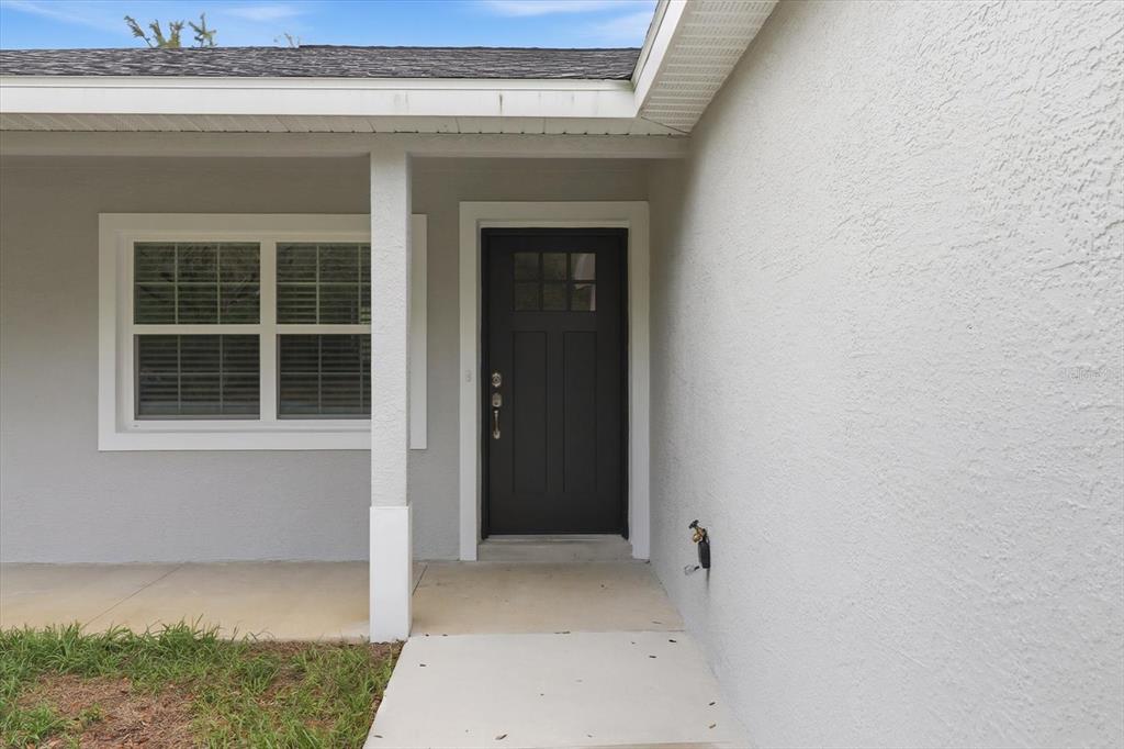 A gray house exterior features a dark front door and a concrete walkway — 8593 N FAUCI POINT, CRYSTAL RIVER, FL