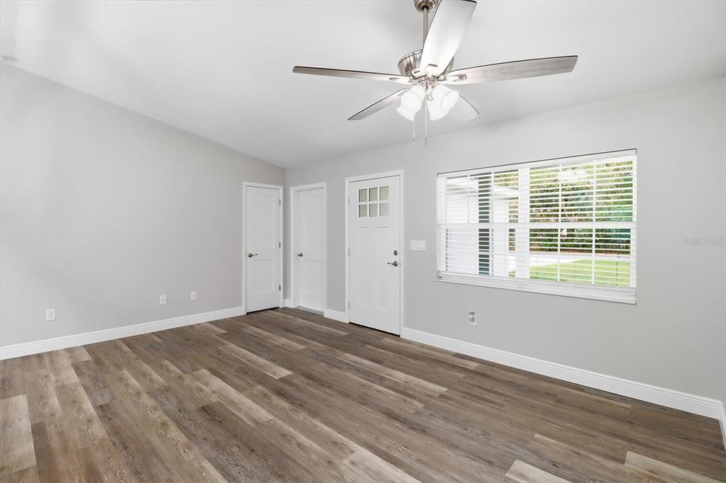 A room with light gray walls, wood-look flooring, a ceiling fan, and a white door — 8593 N FAUCI POINT, CRYSTAL RIVER, FL