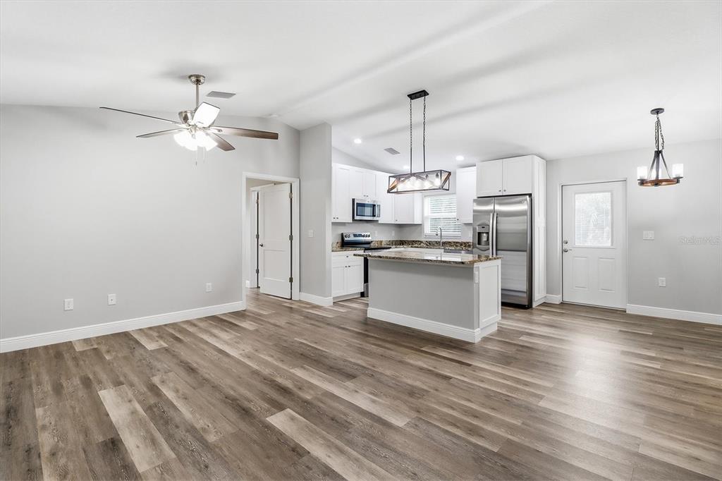 An open-concept kitchen and living area features light gray walls, wood-look flooring, and white cabinetry — 8593 N FAUCI POINT, CRYSTAL RIVER, FL