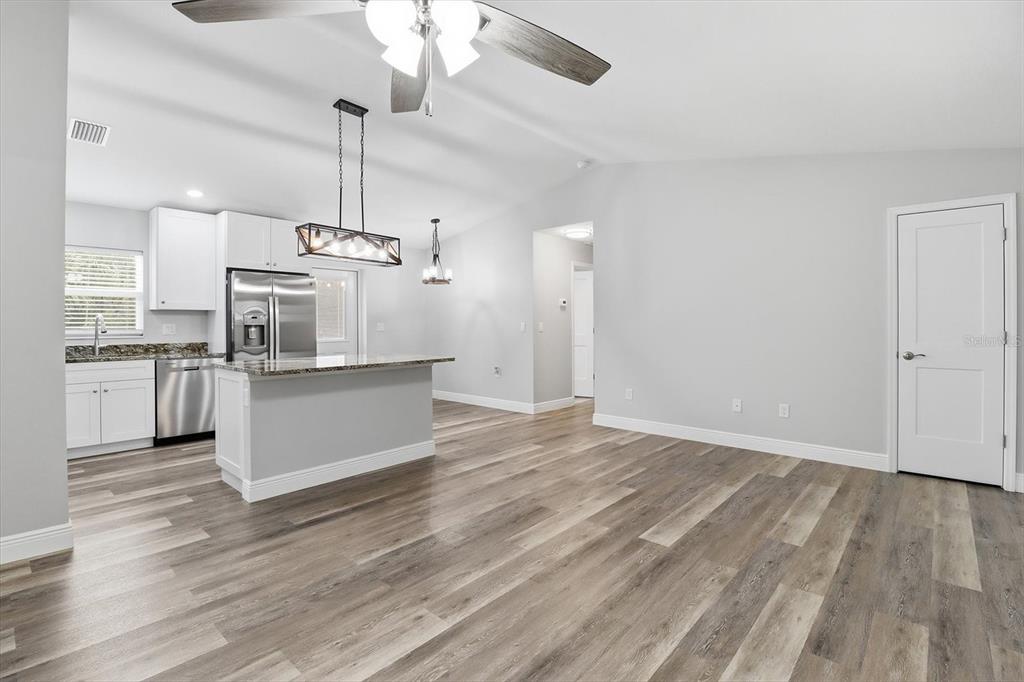 An open-concept kitchen and living area features light gray walls, wood-look flooring, and white cabinetry — 8593 N FAUCI POINT, CRYSTAL RIVER, FL