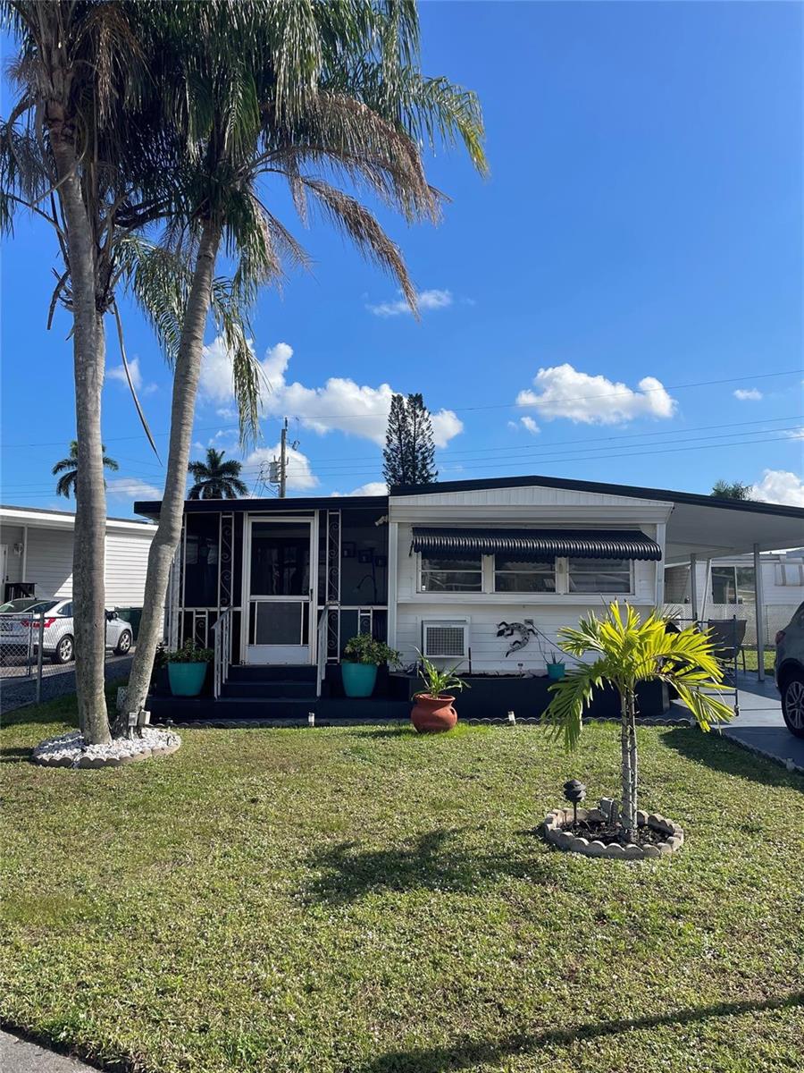 A single-story mobile home with a screened porch, palm trees, and a carport — 8610 SW 18th Court, Davie FL 33324, DAVIE, FL