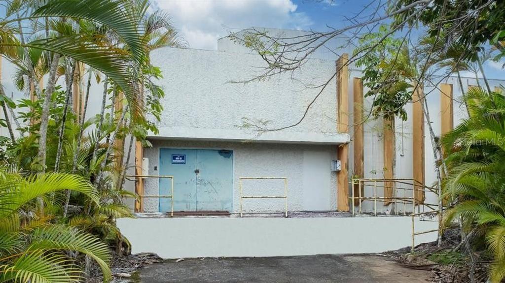 The exterior of a concrete building features a loading dock with blue double doors — Calle 2 PR-7731 INT PR 171, CIDRA, PR