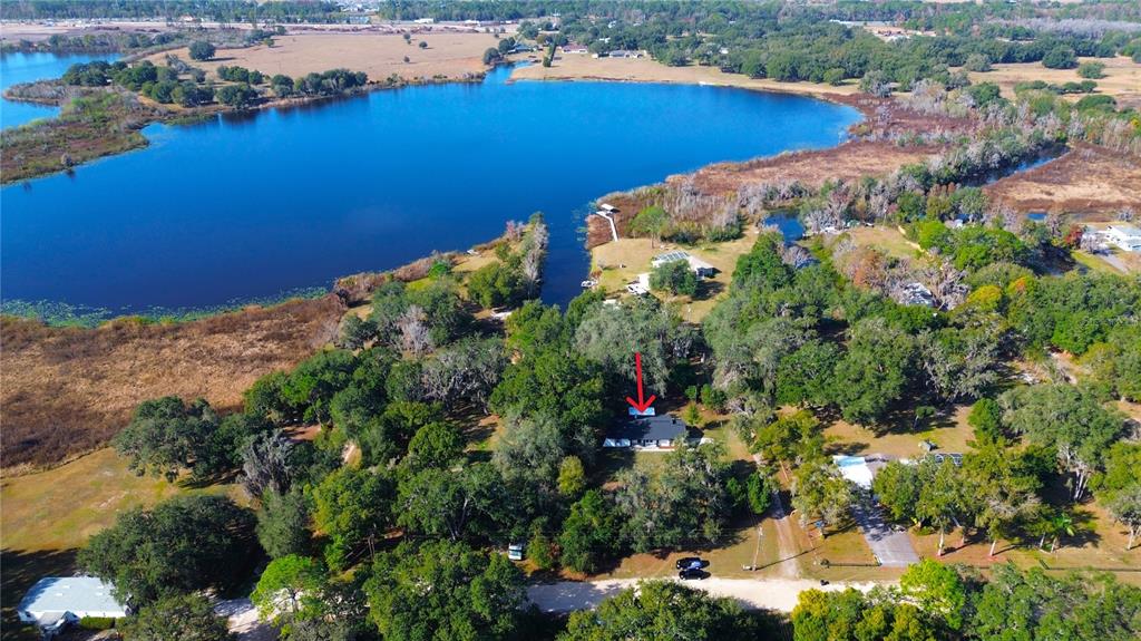 An aerial view shows a house nestled among trees near a large lake — 8807 OVERLOOK DRIVE, WESLEY CHAPEL, FL