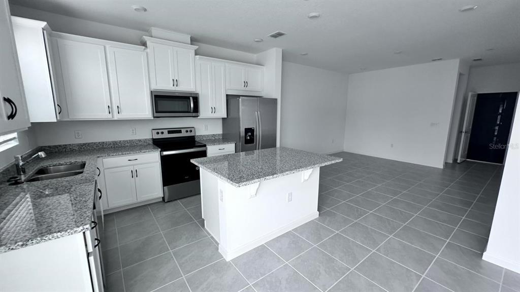 A kitchen features white cabinets, granite countertops, stainless steel appliances, and a central island — 1167 BOARDWALK PLACE, KISSIMMEE, FL