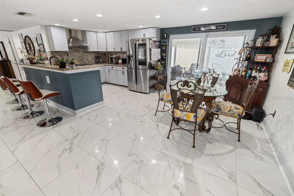 A kitchen and dining area with white marble-look tile floors, white cabinets, and a breakfast bar — 3549 ROCKAWAY DRIVE, HOLIDAY, FL