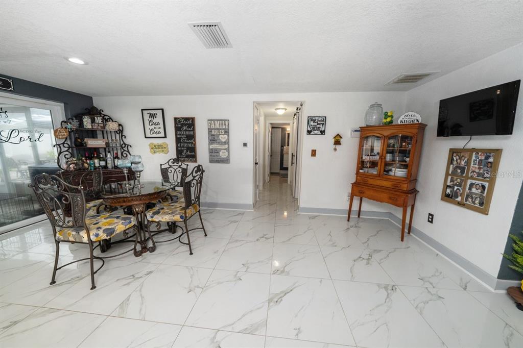 A dining area features white marble-look tile flooring, a glass-top table, and a wooden hutch — 3549 ROCKAWAY DRIVE, HOLIDAY, FL