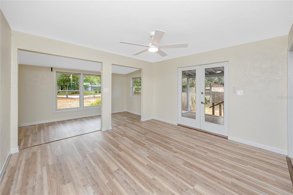 An empty room with light wood-look flooring, a ceiling fan, and glass double doors — 7134 LAUDER PLACE, TAMPA, FL