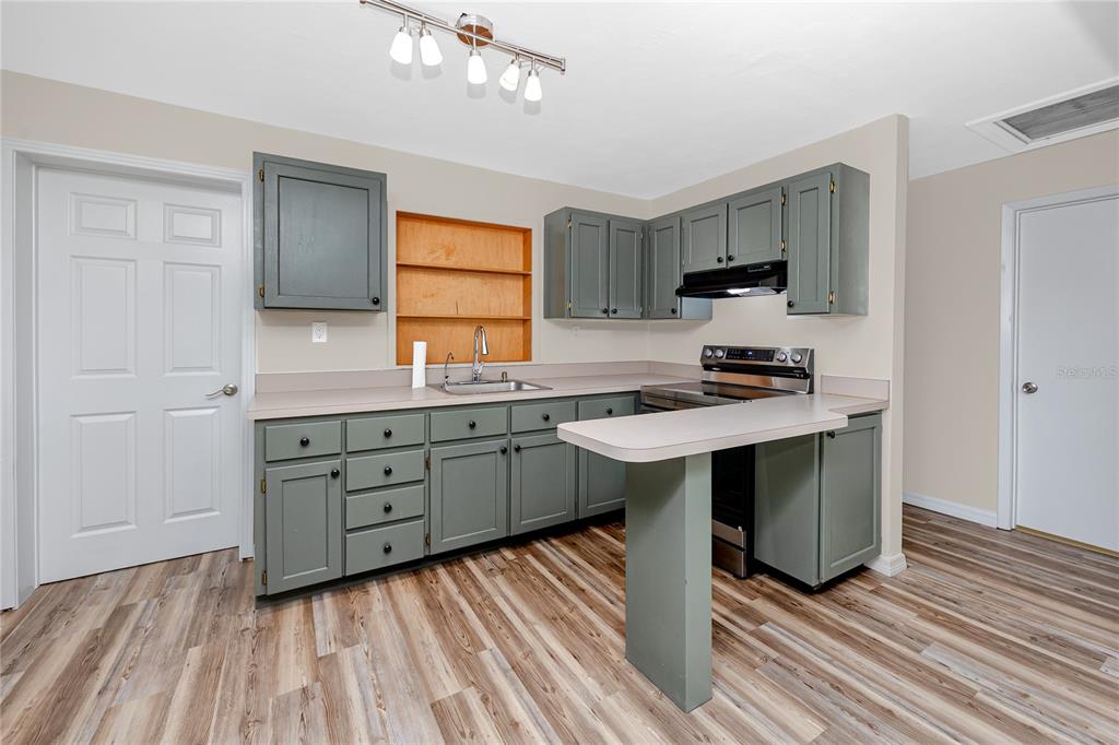A kitchen features gray cabinets, a laminate countertop, and wood-look flooring — 7134 LAUDER PLACE, TAMPA, FL