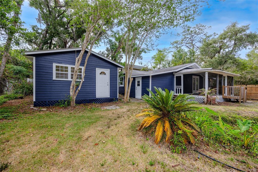 A blue-sided house with a screened-in porch and a detached garage in a wooded yard — 7134 LAUDER PLACE, TAMPA, FL