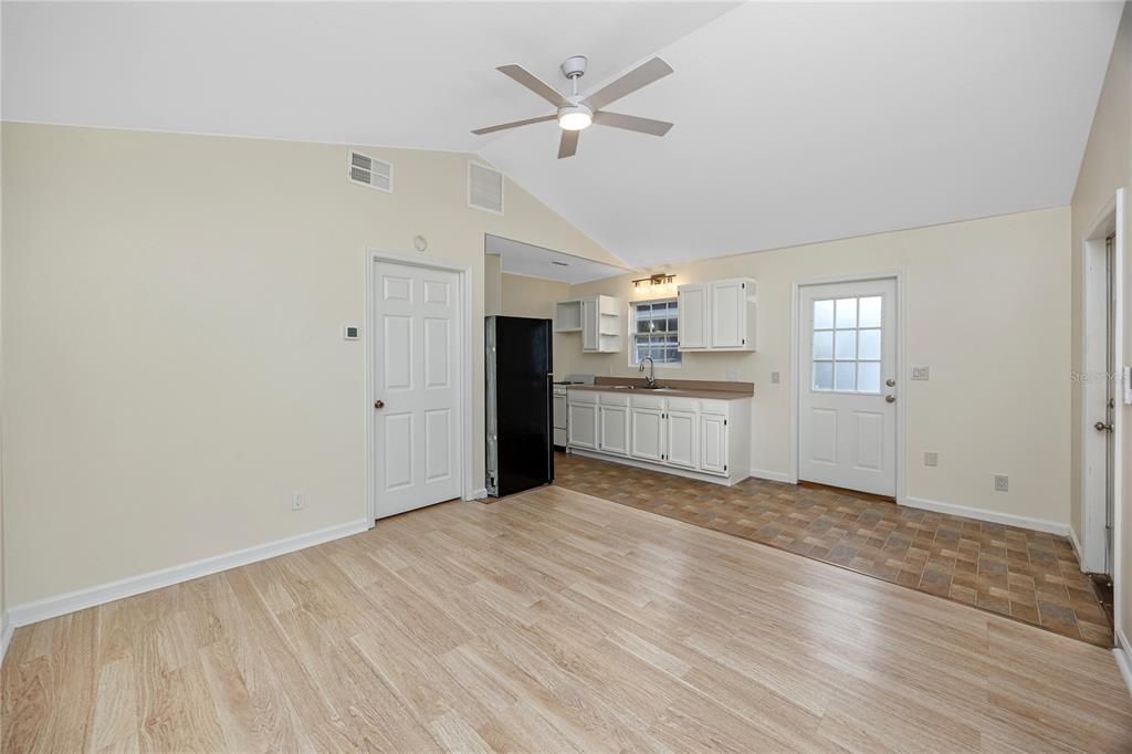 A kitchen and living area with light wood flooring, white cabinets, and a ceiling fan — 7134 LAUDER PLACE, TAMPA, FL